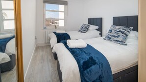 A hotel room with two beds, a window with a view, and a mirror. - Saltwater Apartment Modern 2-bed Waterfront Cowes (Cowes)