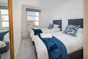 Ein Hotelzimmer mit zwei Betten, einem Fenster mit Blick und einem Spiegel.