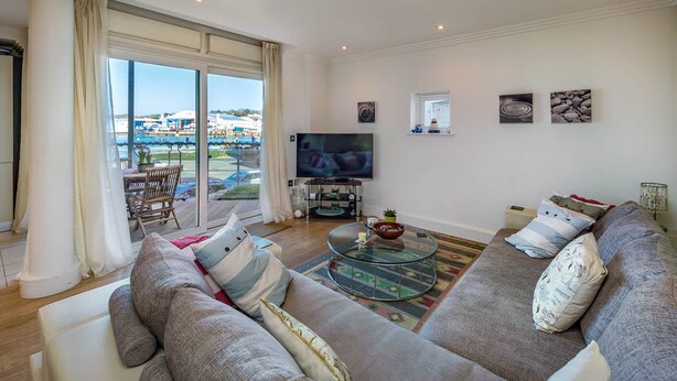 Ein Wohnzimmer mit großem Fenster, einem Flachbildfernseher und einem Sofa.
