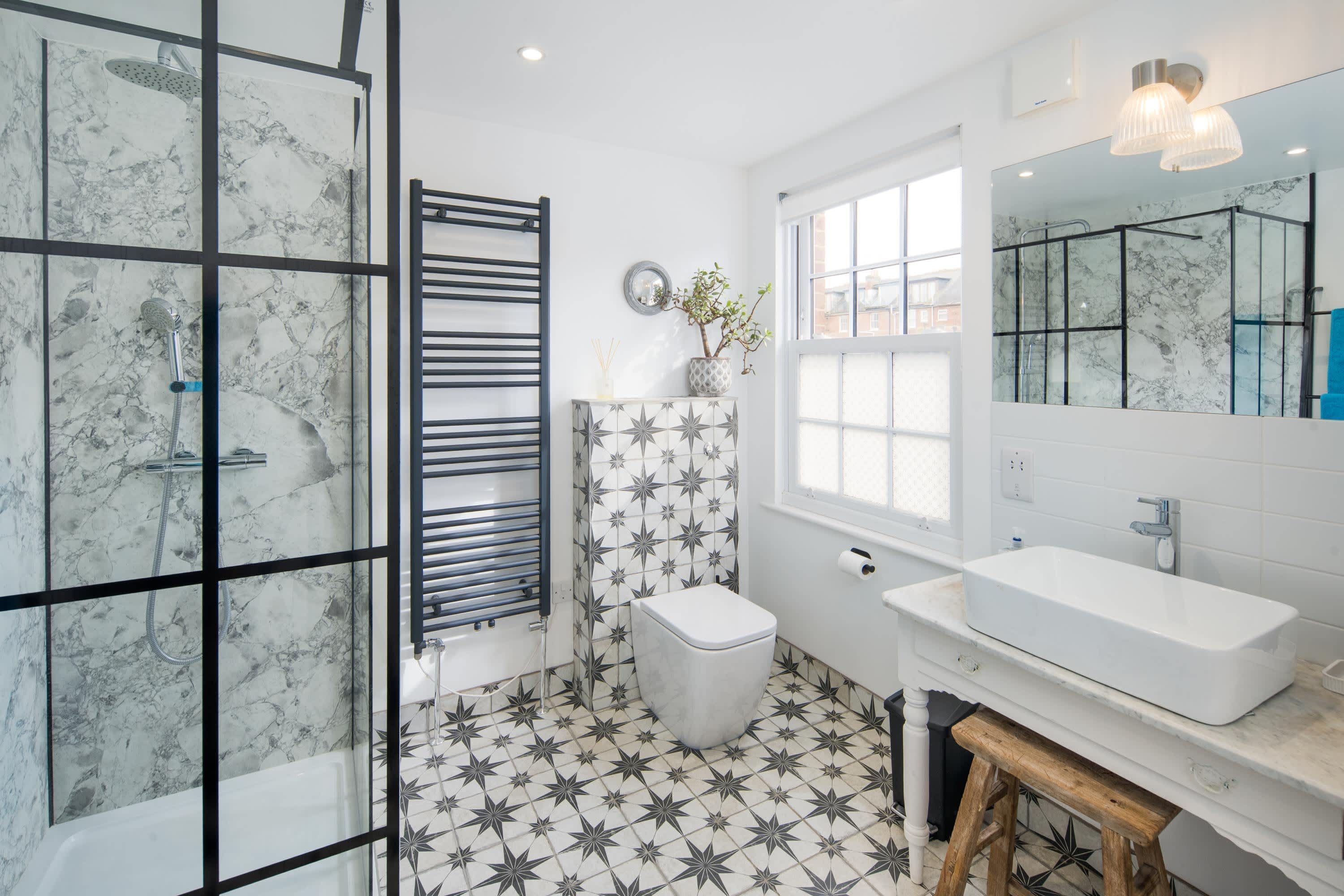 A bathroom with a shower, toilet, sink, and a large mirror.