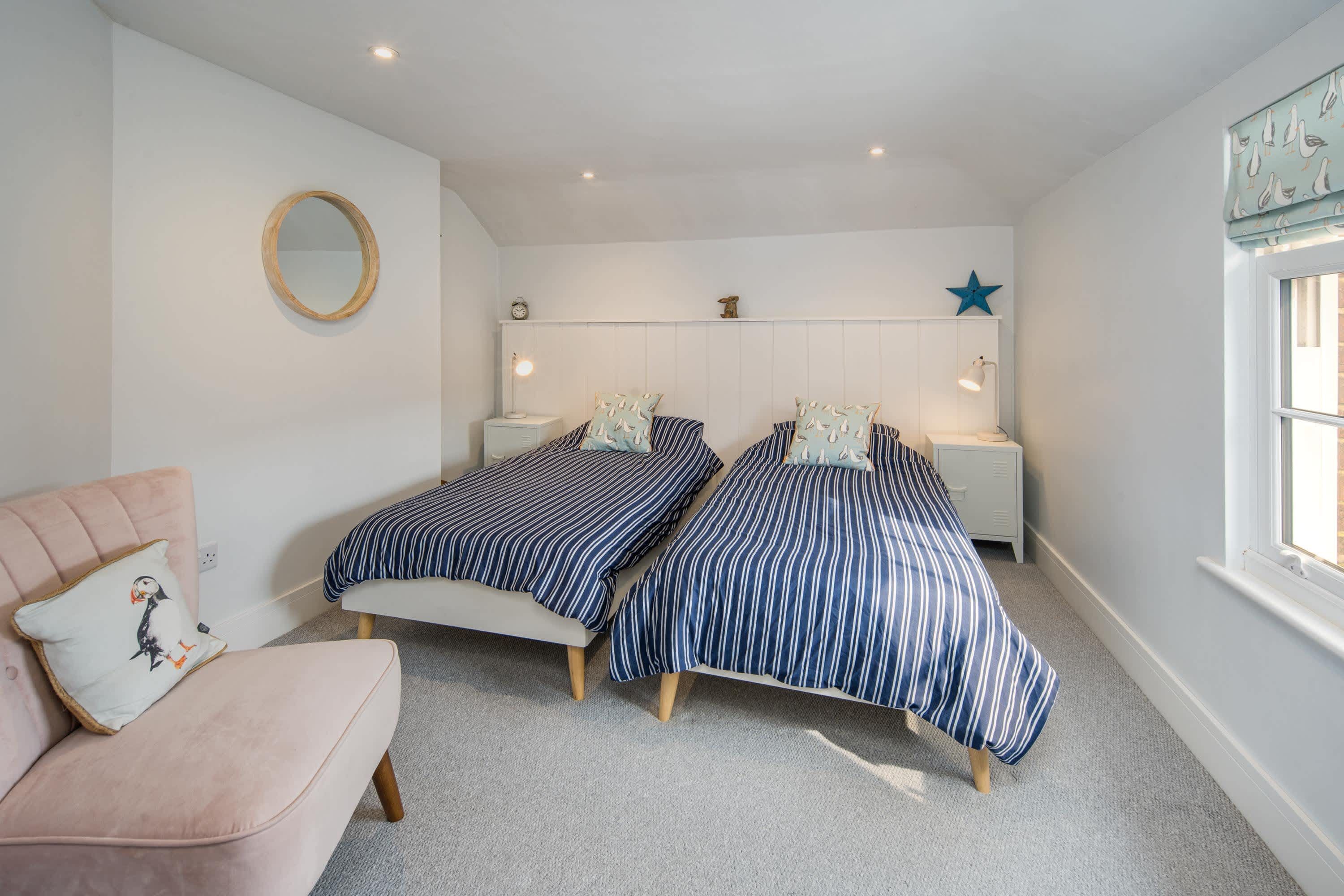 Une chambre avec deux lits, une chaise, un miroir rond, des lampes de chevet et une décoration en forme d’étoile sur le mur.