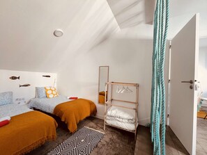 Une chambre avec deux lits, un miroir, un porte-vêtements et une porte donnant sur une autre pièce.