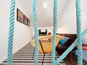 A living room with a sofa, a yellow chair, a TV, and a striped rug. - Apartment, Portas Residence (Ponta Delgada)