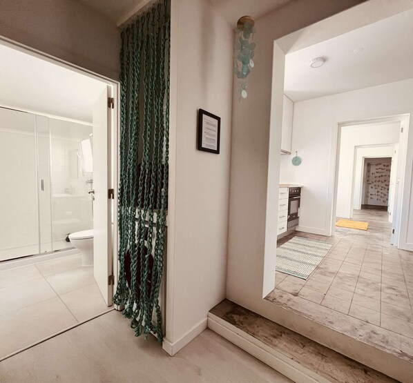 A hallway with a green curtain, a framed certificate, and a kitchen area with cabinets and a stove. - Apartment, Portas Residence (Ponta Delgada)