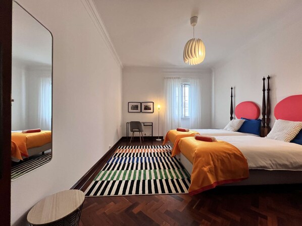 Une chambre d’hôtel avec un grand lit, un bureau, une chaise, un miroir et un tapis à motifs.
