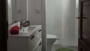 Un baño con lavamanos blanco, espejo y retrete.