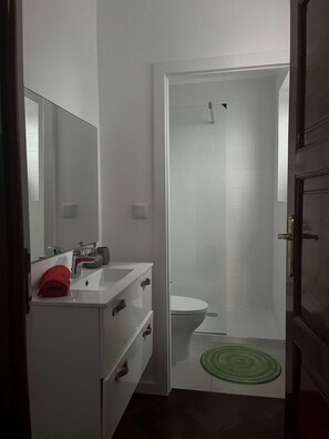 Une salle de bain avec un lavabo blanc, un miroir et des toilettes.