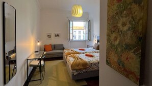 Una habitación de hotel moderna con cama, escritorio, silla, espejo, un cuadro y ventana.