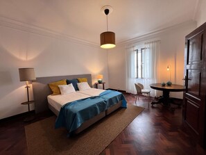 Une chambre d’hôtel avec un lit, des tables de chevet, un bureau et une chaise.