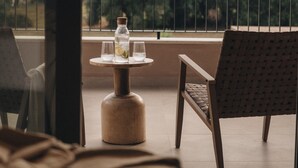 Ein Balkon mit Tisch, zwei Stühlen und einer Wasserflasche.