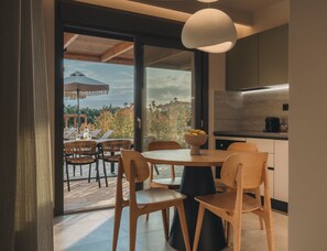 Un comedor moderno con una mesa redonda, sillas de madera y vistas al exterior a través de grandes puertas de cristal.