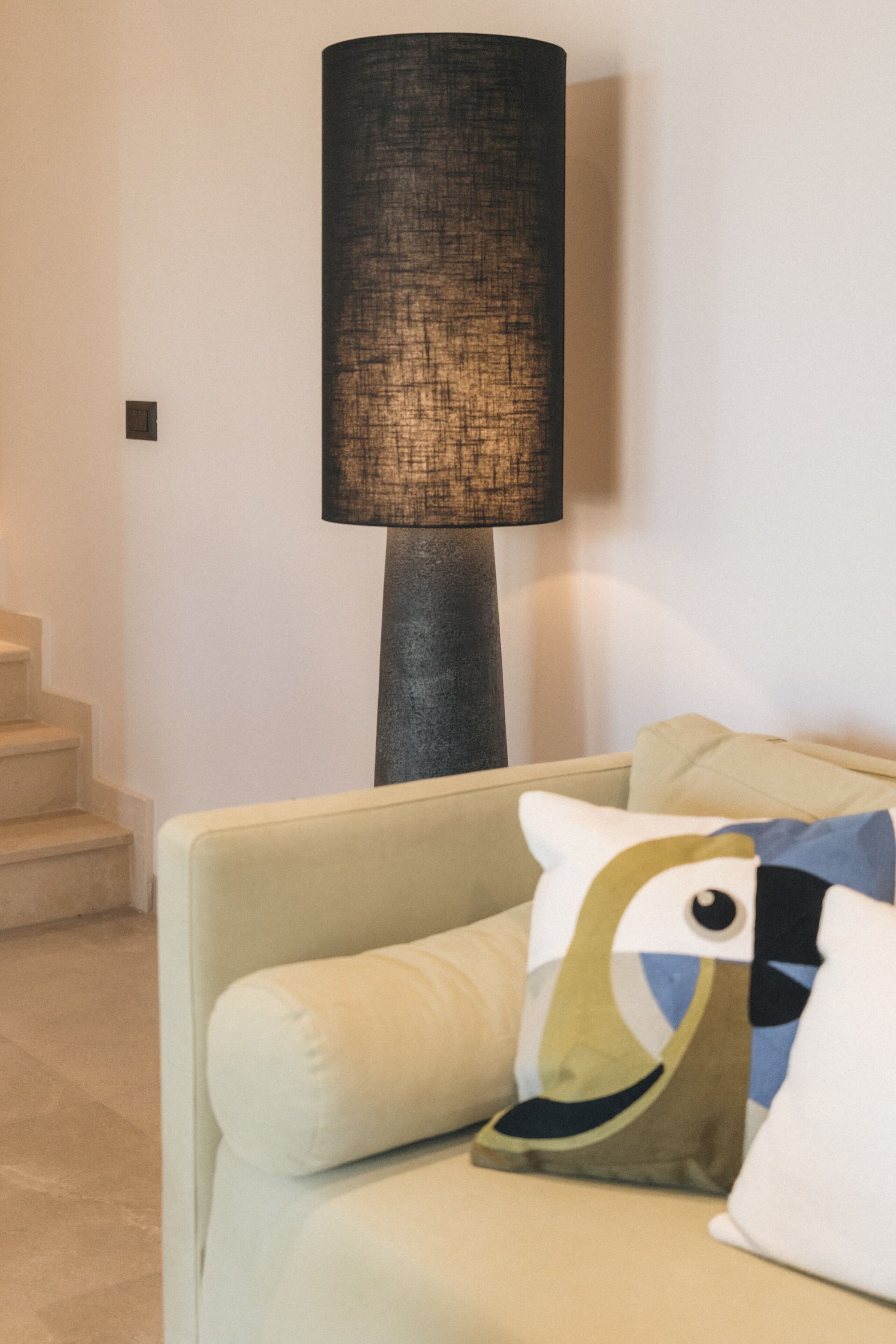 A room with a sofa, a lamp, and a staircase.