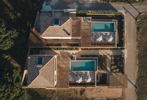 An aerial view of a property with two swimming pools, a covered patio, and a stone facade. - ORA BLU (PREVEZA)