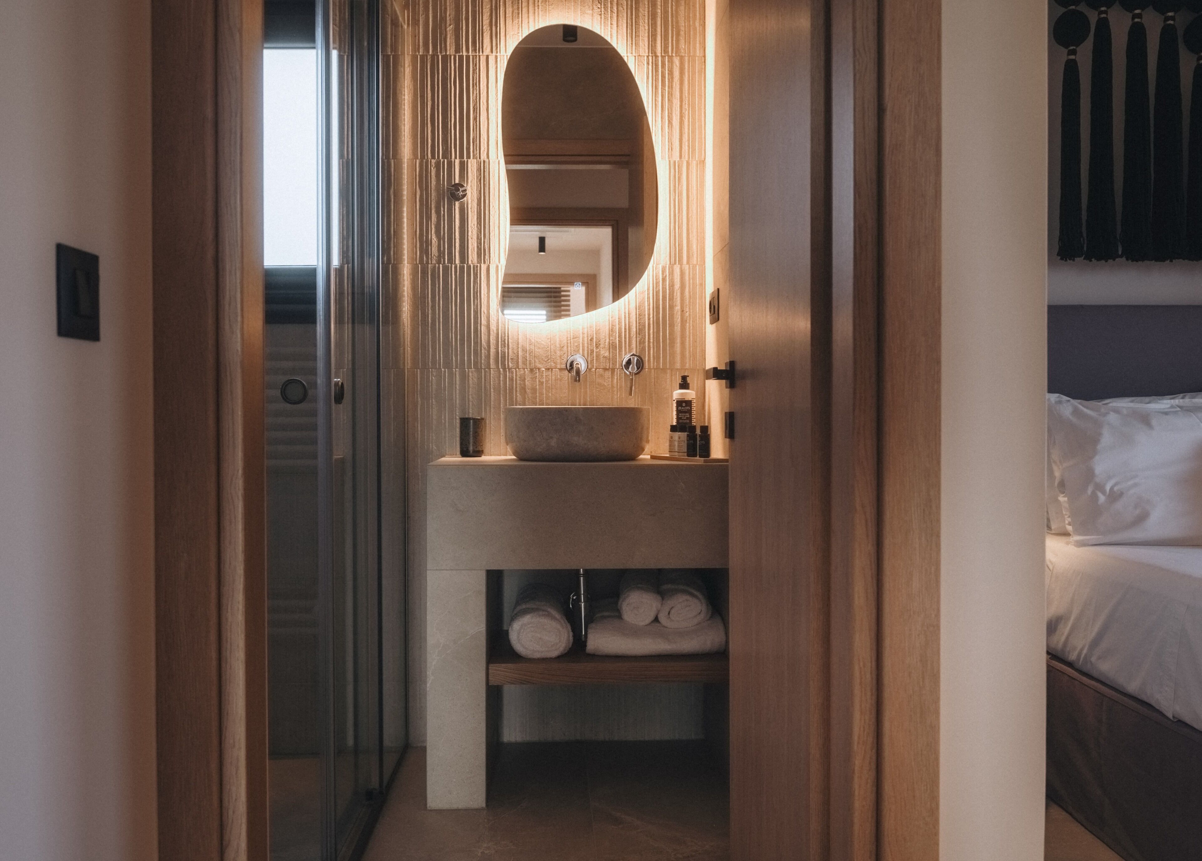 A modern bathroom with a large oval mirror, a sink, and a towel rack.