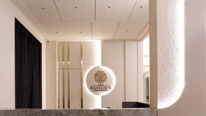 En receptionsdisk med en marmortop og et logo, der viser 'BASILICA REDISCOVER SENSITIVITY'.