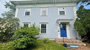 A two-story house with a blue door, white trim, and a small front porch. - Original School House in the Heart of Chatham (Chatham)