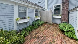 A residential property with a brick pathway, white window boxes with plants, and a wooden fence. - Original School House in the Heart of Chatham (Chatham)