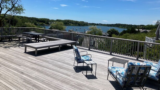 A deck with outdoor furniture, a railing, and a view of a lake. - Original School House in the Heart of Chatham (Chatham)
