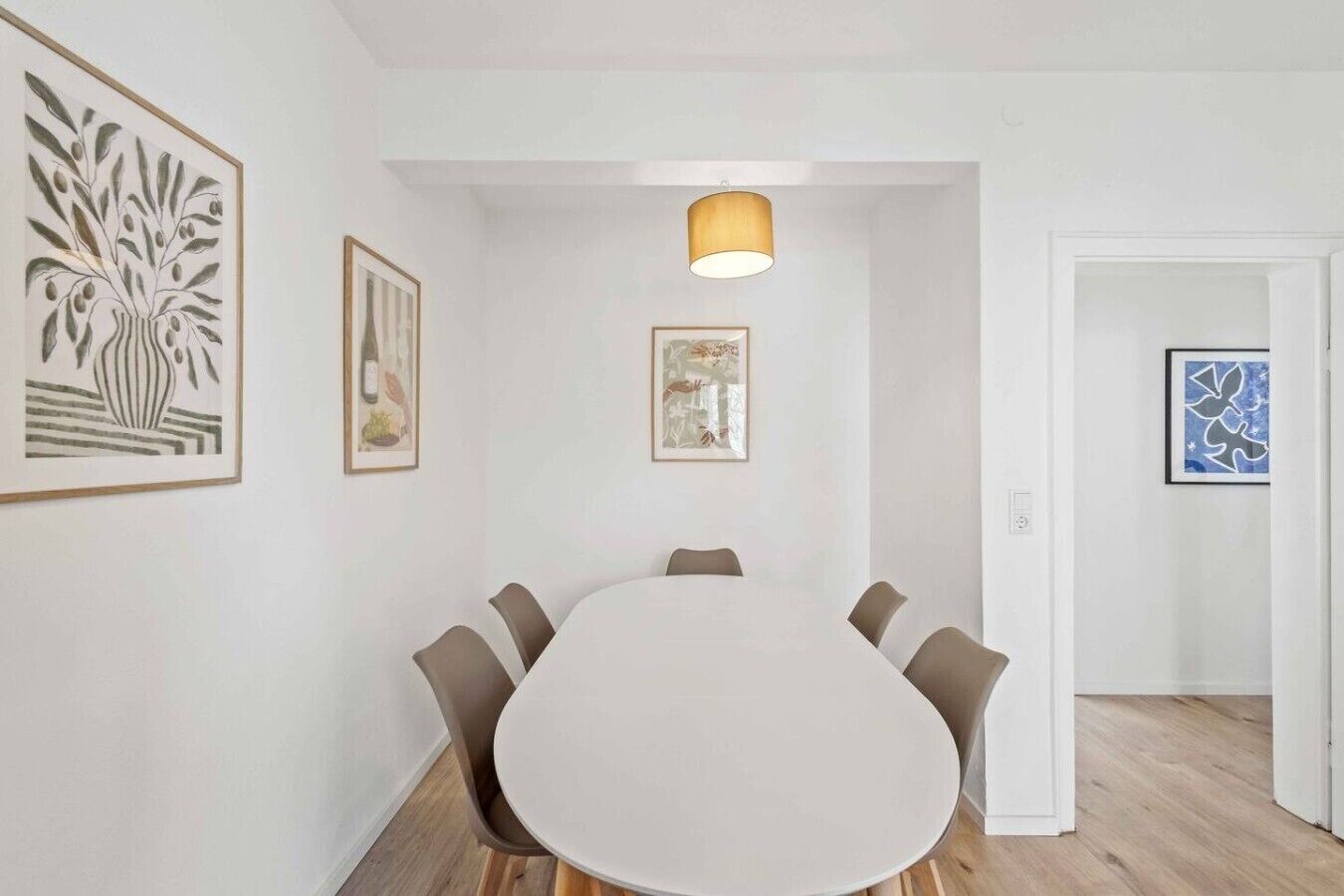 Une salle de conférence équipée d’une table ronde, de six chaises et d’œuvres d’art encadrées accrochées aux murs.