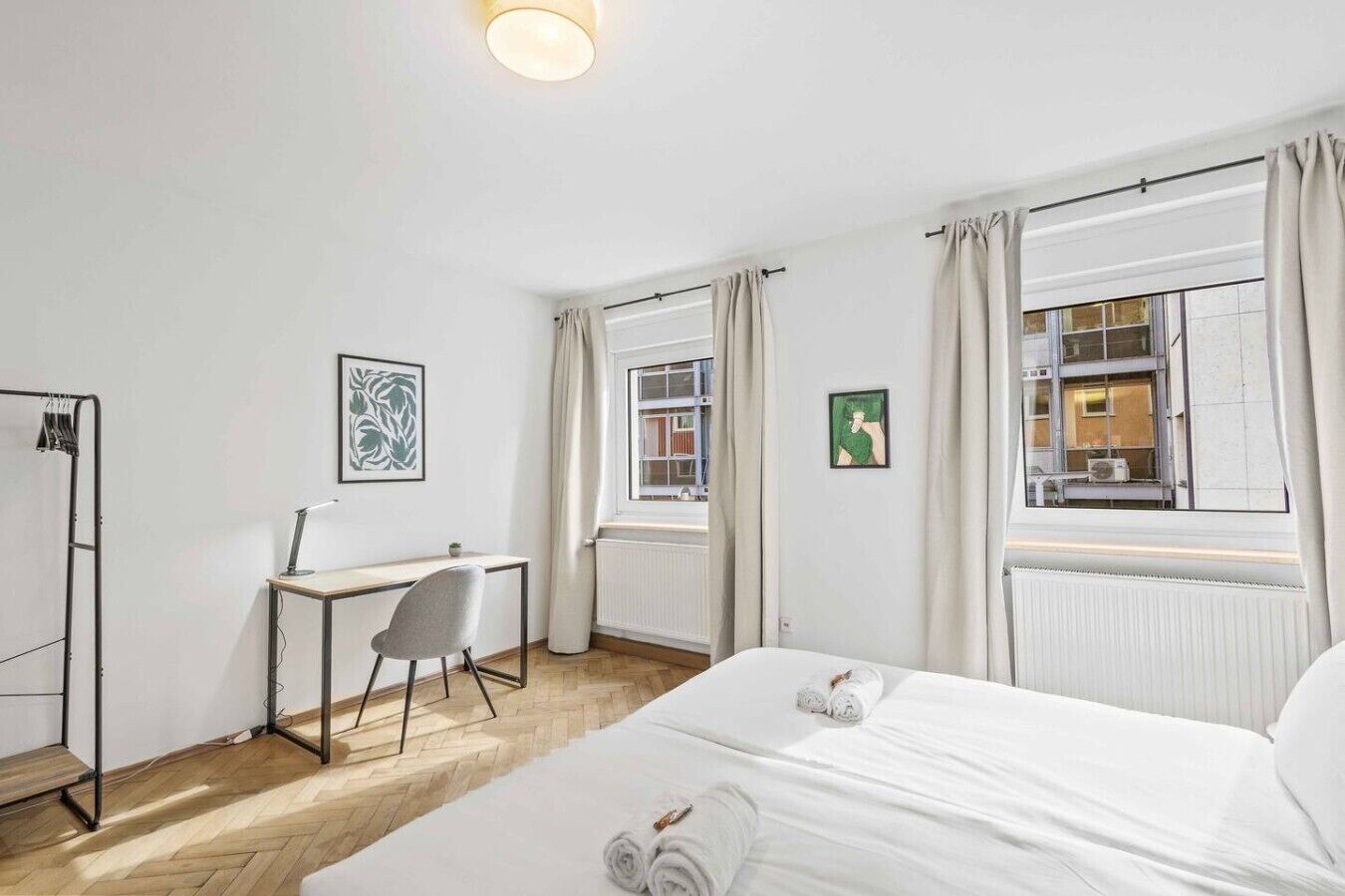 Une chambre d’hôtel avec un lit, un bureau, une chaise et un radiateur.
