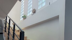 A staircase with wooden steps and black railings, leading to a landing with a potted plant and a wall-mounted decorative item.