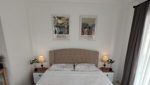 A neatly made bed with a floral bedspread, two bedside tables with lamps, and two wall art pieces.