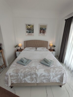 A neatly made bed with a floral bedspread, two bedside tables with lamps, and two wall art pieces.