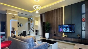 Una sala de estar moderna con un sofá gris, una mesa de centro y un televisor montado en la pared.
