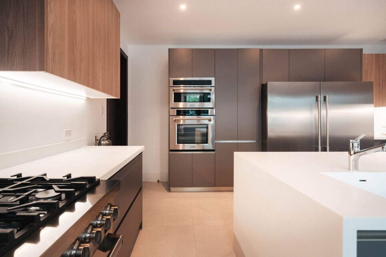A modern kitchen with stainless steel appliances, a gas stove, and wooden cabinetry.
