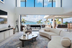 A modern living room with a large sofa, a coffee table, and a view of the beach. - Bocobay Palm Beach Villas (St. Anns Bay)