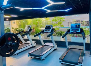 A gym with treadmills, a weight bench, and a digital display. - Stylish 2 Bedroom Apartment in Nairobi with Gym, WiFi, and 24/7 Security (Nairobi)