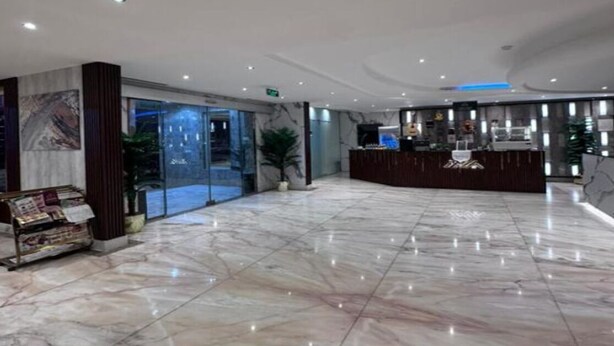 A hotel lobby with a reception desk, marble flooring, and a glass door entrance. - Life Suites Serviced Apartments (Riyadh)