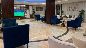 A spacious lobby with a large TV screen, comfortable seating, and a marble floor. - Life Suites Serviced Apartments (Riyadh)