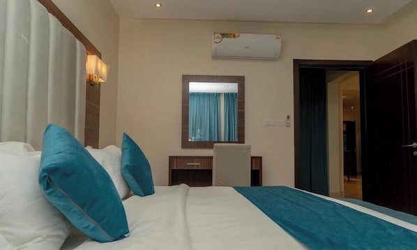 A hotel room with a bed, a desk, a mirror, and an air conditioning unit. - Life Suites Serviced Apartments (Riyadh)