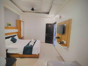 A hotel room with a bed, a desk with a computer, a TV, and a door. - Hotel Sai Nanda Shirdi (Shirdi)