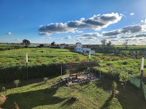 Eine ländliche Landschaft mit einem weißen Gebäude, einem Gebäude mit Strohdach und einem Feld.