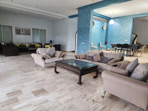 Un salon spacieux avec une grande table basse, des canapés et un coin repas comprenant des chaises et une table.