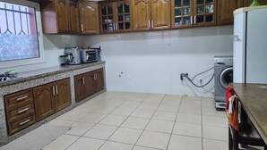 Una cocina con armarios de madera, lavadora y una encimera con electrodomésticos.