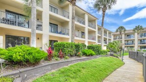 A multi-story hotel with balconies, a wooden boardwalk, and well-maintained landscaping. - First Floor Condo, Two Pools, One Heated Pool, Easy Beach Access, Large Patio, $300 in Free Tickets! (St. Augustine Beach)