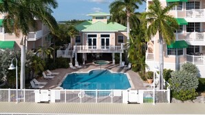 A hotel with a pool, lounge chairs, and a view of the ocean. - Sunset Paradise at Sunset Marina-2 bed 2 bath oceanfront condo (Key West)
