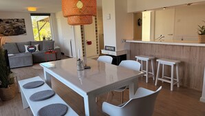 Ett modernt kök med en vit bänkskiva, en orange hänglampa och en skylt med texten ”TORMENTIL”.