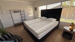 Ein Schlafzimmer mit Bett, einer Leiter, einem kleinen Tisch und einem Fenster mit Jalousien.