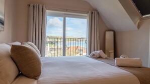 Et hotelværelse med en stor seng, havudsigt og en balkon med gelænder.