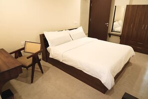 A neatly arranged bedroom with a bed, a chair, a desk, and a wardrobe. - Bani Park Boutique · Modern Luxe 2BR Apartment (Jaipur)