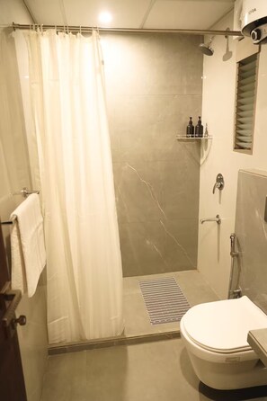 Et badeværelse med bruser, toilet og håndklædeholder.