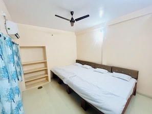 A bedroom with a bed, a ceiling fan, a wardrobe, and a window.