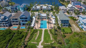 Vista aérea de un resort con varias edificaciones, una piscina central y céspedes bien cuidados.