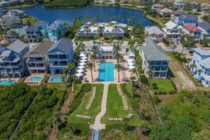 Eine Vogelperspektive eines Resorts mit mehreren Gebäuden, einem zentralen Swimmingpool und gepflegten Rasenflächen.