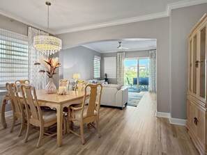 Ein Essbereich mit Holztisch und -stühlen, einer Chandelierleuchtre und Blick auf einen Balkon mit Gartenmöbeln.