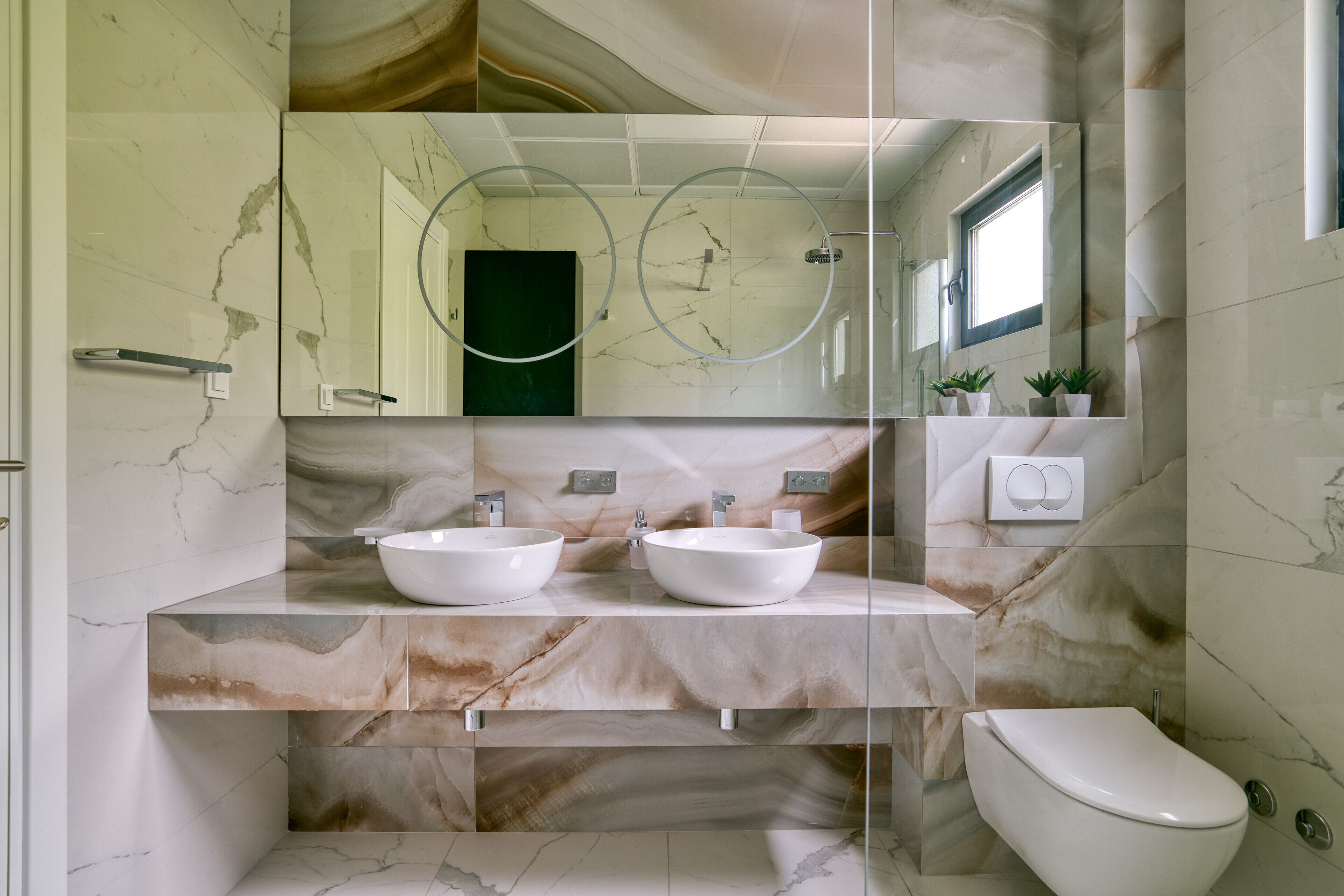 A bathroom with two sinks, a toilet, and a large mirror.